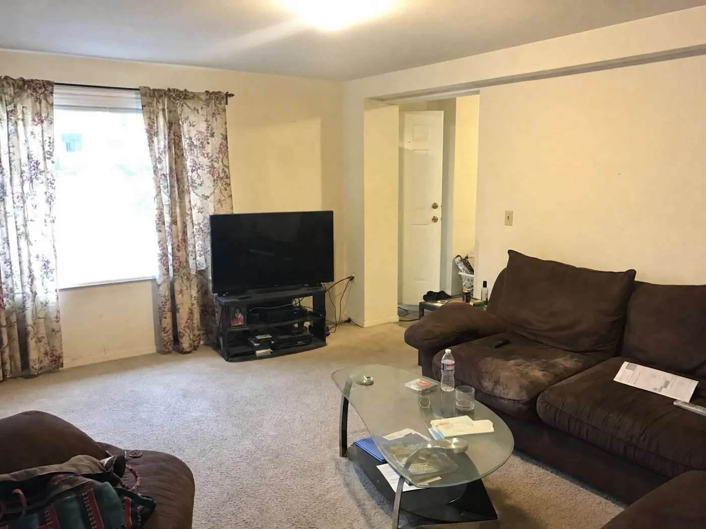 Dated beige living room with a worn brown sofa before redesign