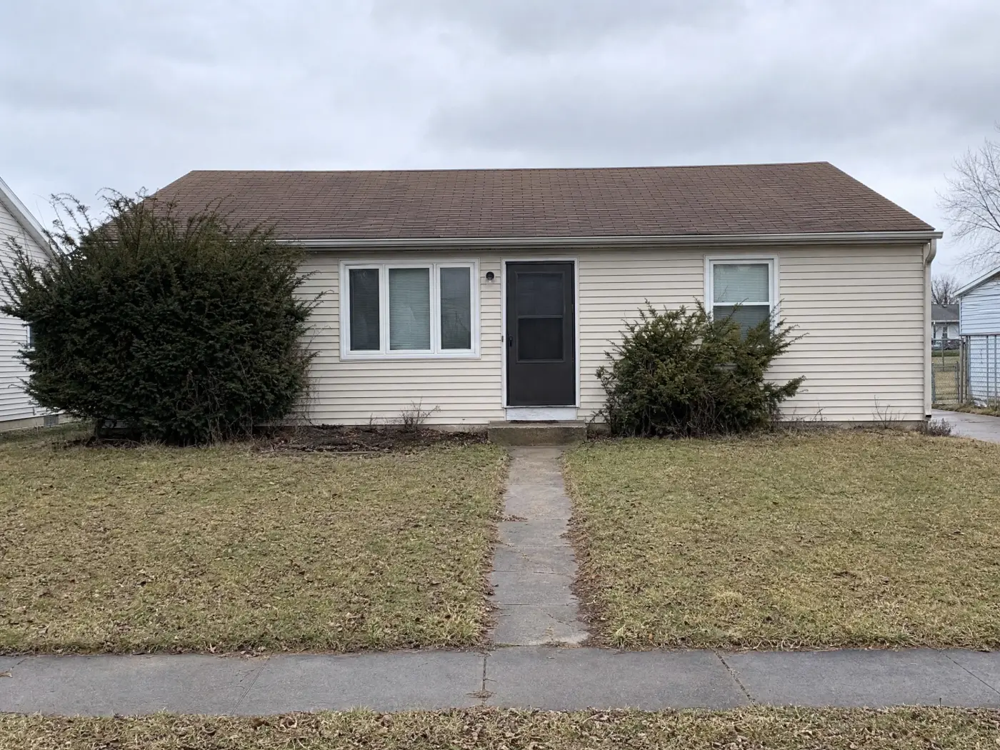A plain front yard with a worn lawn and empty foundation bed, the starting point for AI Ideas in Idori